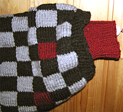 Detaljbild p� �rmlinningen p� Svart och gr�rutig polotr�ja med vinr�da knater och en och annan vinr�d ruta