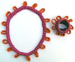 Resrstickat rosa hals- och armband med ringar.