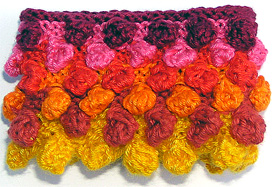 Rtstickat armband med moucher i olika gul-orange-rosa frger.